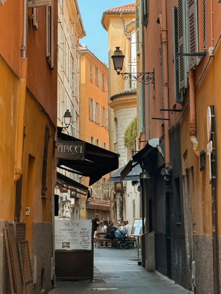 Picturesque narrow street in Vieux Nice showcasing the vibrant ochre and pink Italianate buildings of the medieval old town — the city's most atmospheric district shaped by 472 years of Savoyard rule
