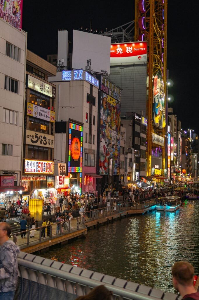 Lively night scene on Dotonbori Canal in Osaka with bustling crowds and illuminated neon signs