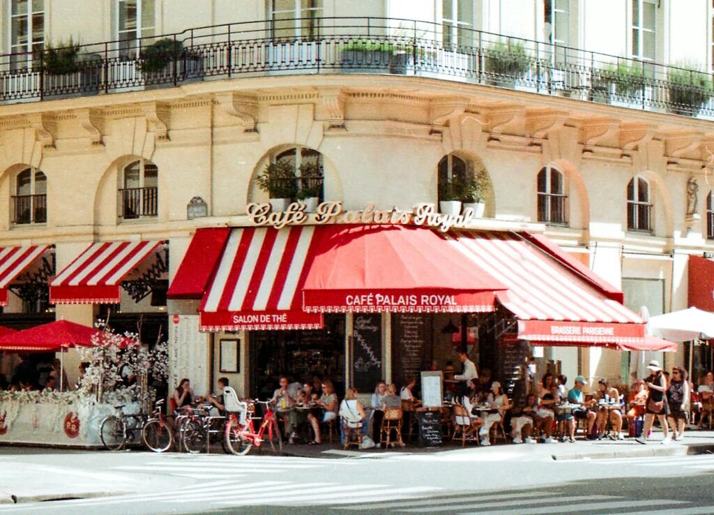 A classic Parisian café terrace with red awnings, bistro tables, and outdoor seating in central Paris