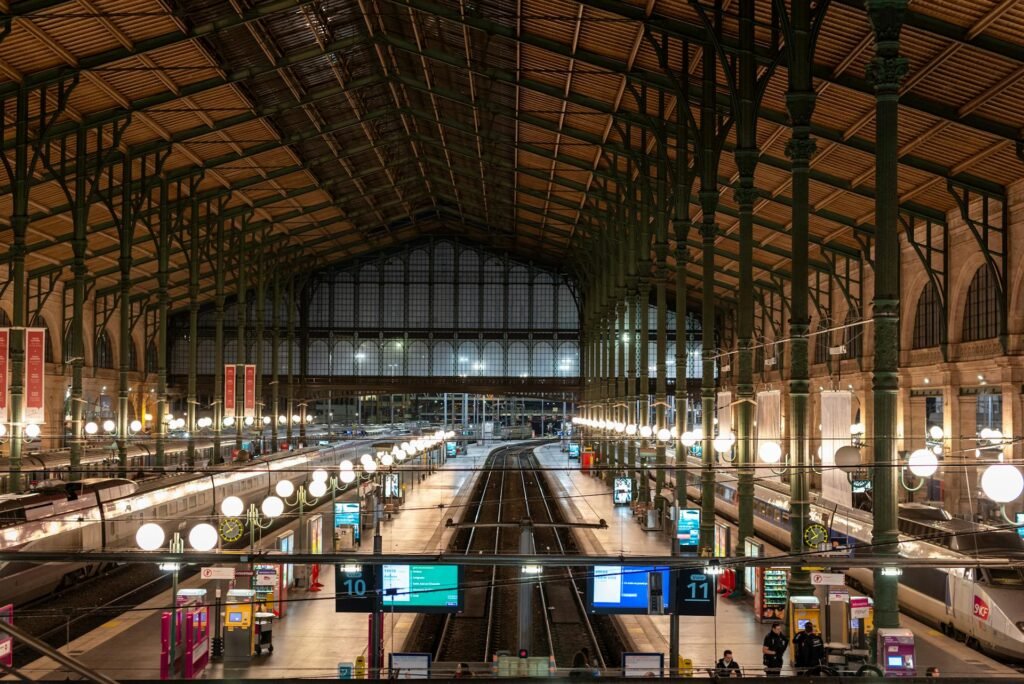 Interior view of Gare du Nord train station in Paris at night, with trains and architectural details visible