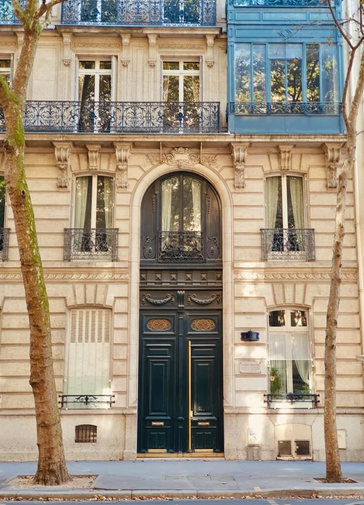 Elegant Haussmann-style building facade in central Paris during autumn, with cream-colored limestone and wrought-iron balconies