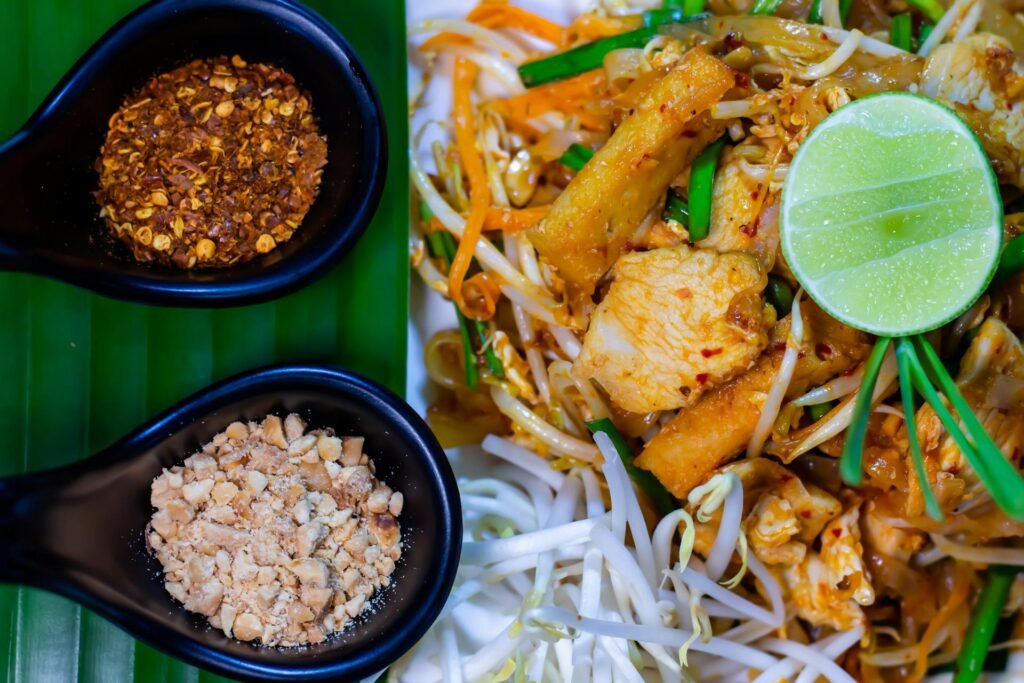 Delicious traditional Pad Thai noodles served with lime, peanuts, and chili flakes — Thailand's signature dish