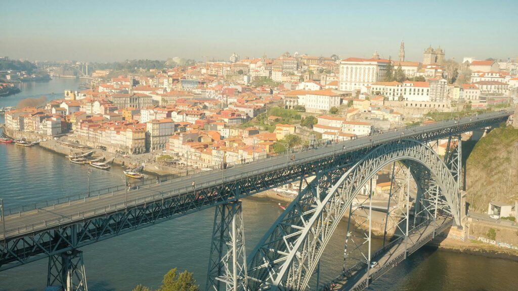 Panoramic aerial view of Porto featuring the iconic Dom Luís I Bridge — the 1881 double-decker iron bridge designed by Téophile Seyrig (Eiffel's business partner) connecting Porto and Vila Nova de Gaia across the Douro River