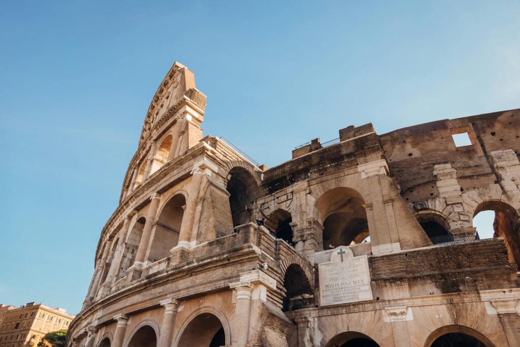 The Colosseum in Rome on a sunny day, showcasing the ancient amphitheater's distinctive arches and stonework