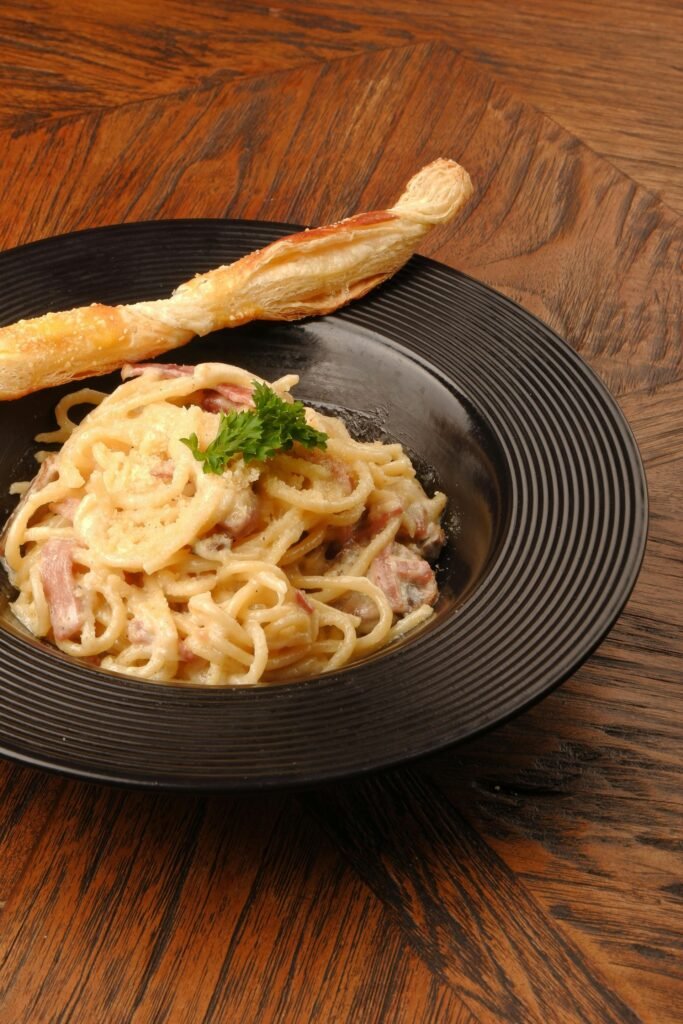 A plate of creamy spaghetti carbonara on a wooden table, one of Rome's four iconic pasta dishes