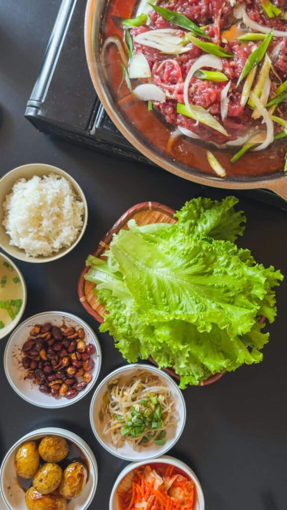A Korean BBQ set featuring bulgogi and traditional banchan side dishes served with fresh lettuce wraps