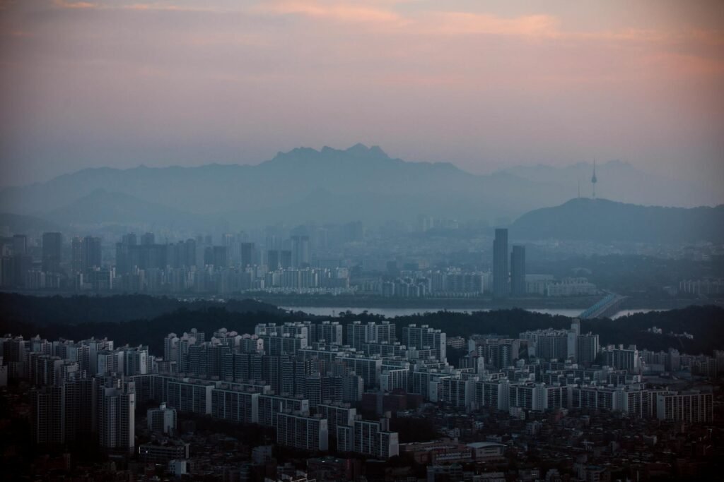 Aerial view of Seoul's skyline with misty mountains and Namsan Tower in the background