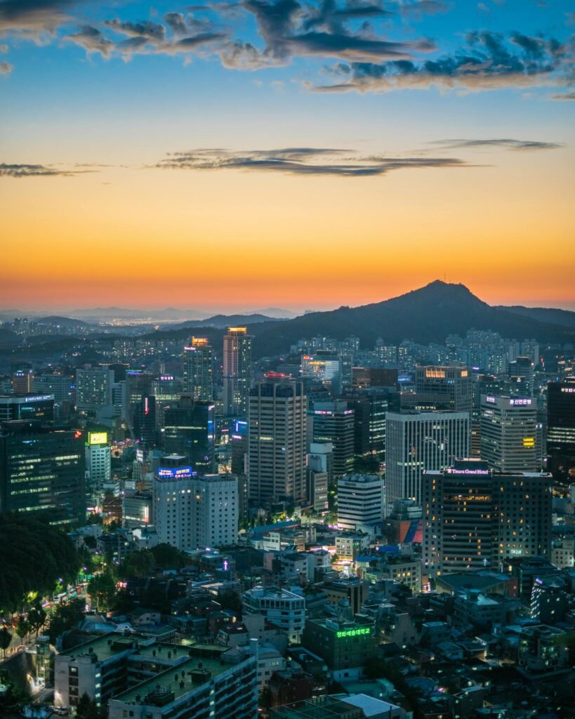 Twilight view of Seoul's skyline with skyscrapers and the surrounding mountains during golden hour