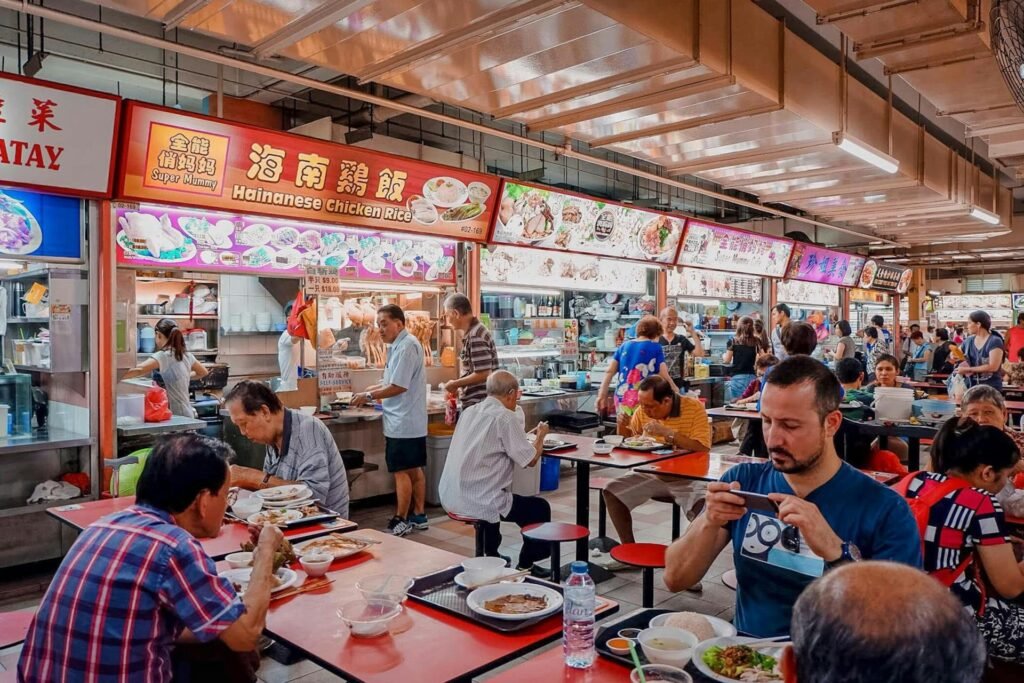 Bustling Singapore hawker center with diners enjoying Hainanese chicken rice and various dishes — UNESCO heritage food culture