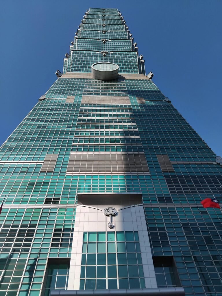 Upward view of Taipei 101 against blue sky showcasing its bamboo-segmented modern architecture