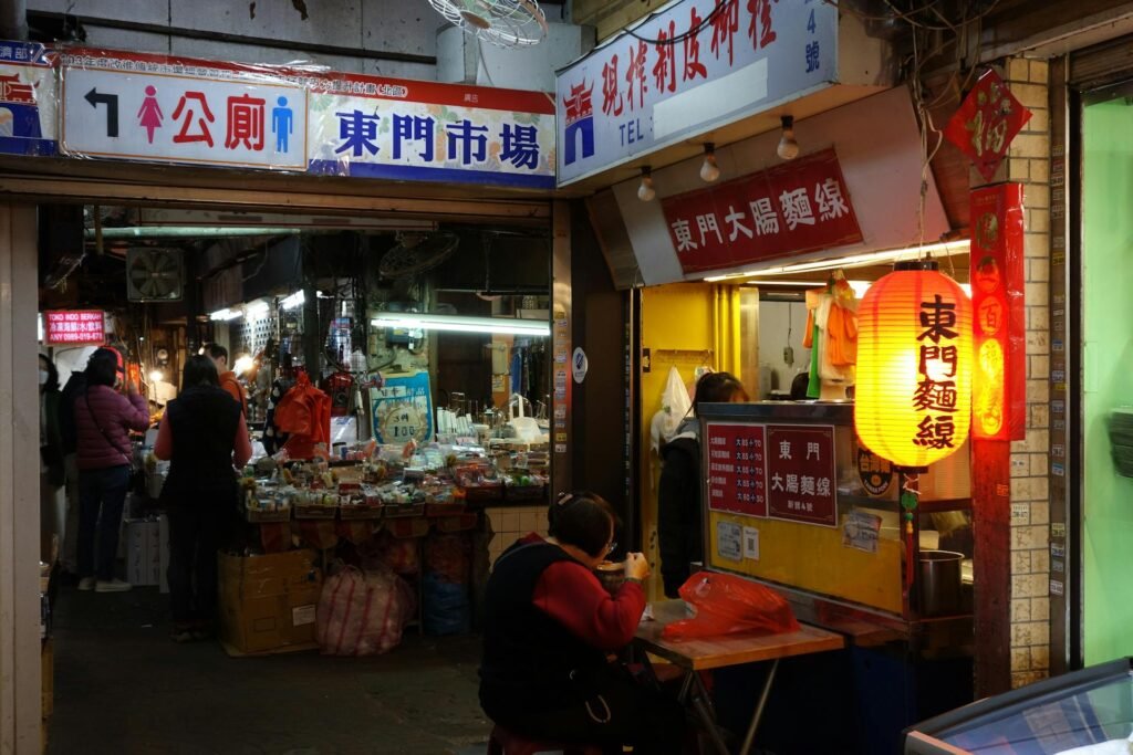 Vibrant night market scene in a Taipei district with food stalls, neon signs, and busy crowds