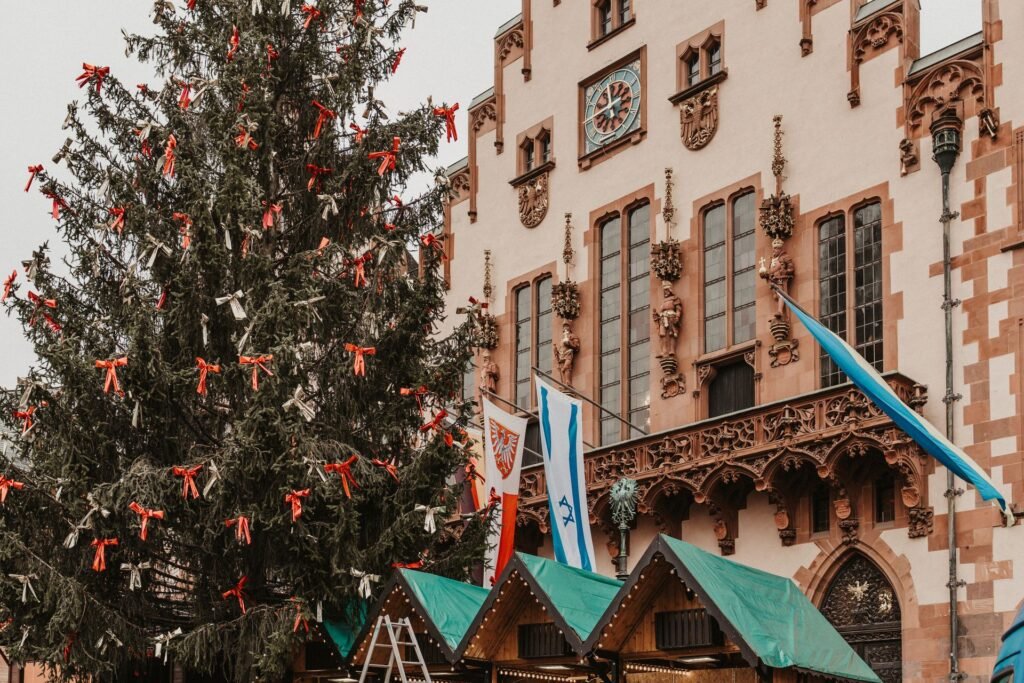 A decorated Christmas tree and market stalls in front of the historic Römer building during Frankfurt's Christmas market