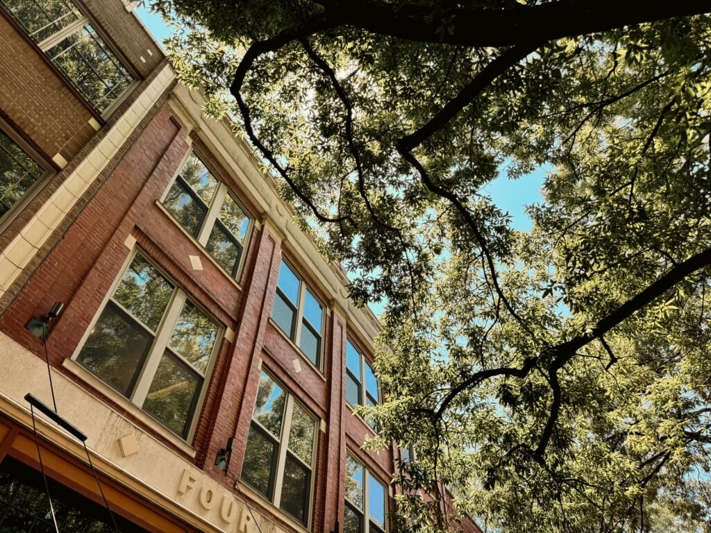 Restored early-1900s brick buildings under a leafy tree canopy in downtown Knoxville, the walkable historic core where many hotels and stays are located