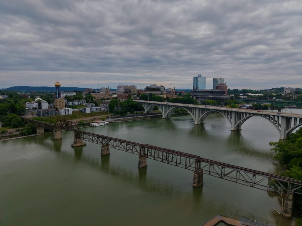 Aerial view of the downtown Knoxville skyline with road and rail bridges spanning the Tennessee River, the largest city in East Tennessee set against the Appalachian foothills