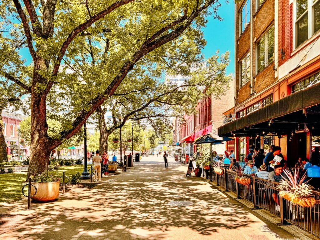 Market Square in downtown Knoxville on a sunny day, a tree-lined pedestrian plaza lined with sidewalk cafes and restaurants