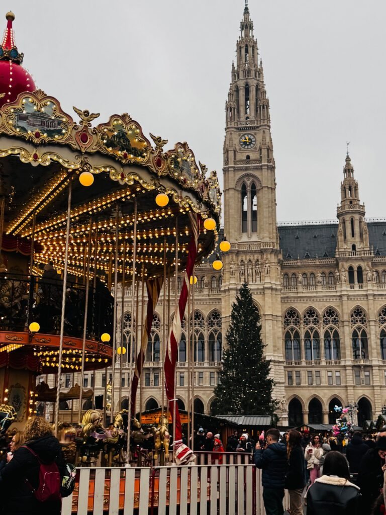 Vienna's Christkindlmarkt at the Rathaus, with an illuminated carousel and Christmas tree before the Gothic City Hall