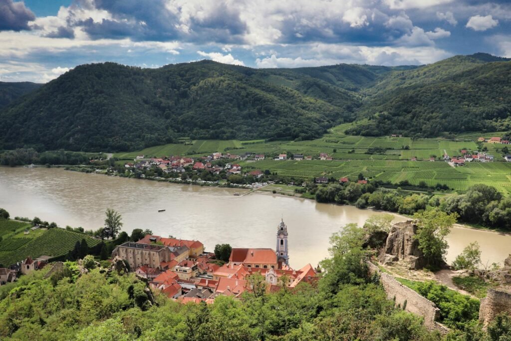 Aerial view of Dürnstein on the Danube in the Wachau valley, with vineyards and a blue baroque church tower, a day trip from Vienna